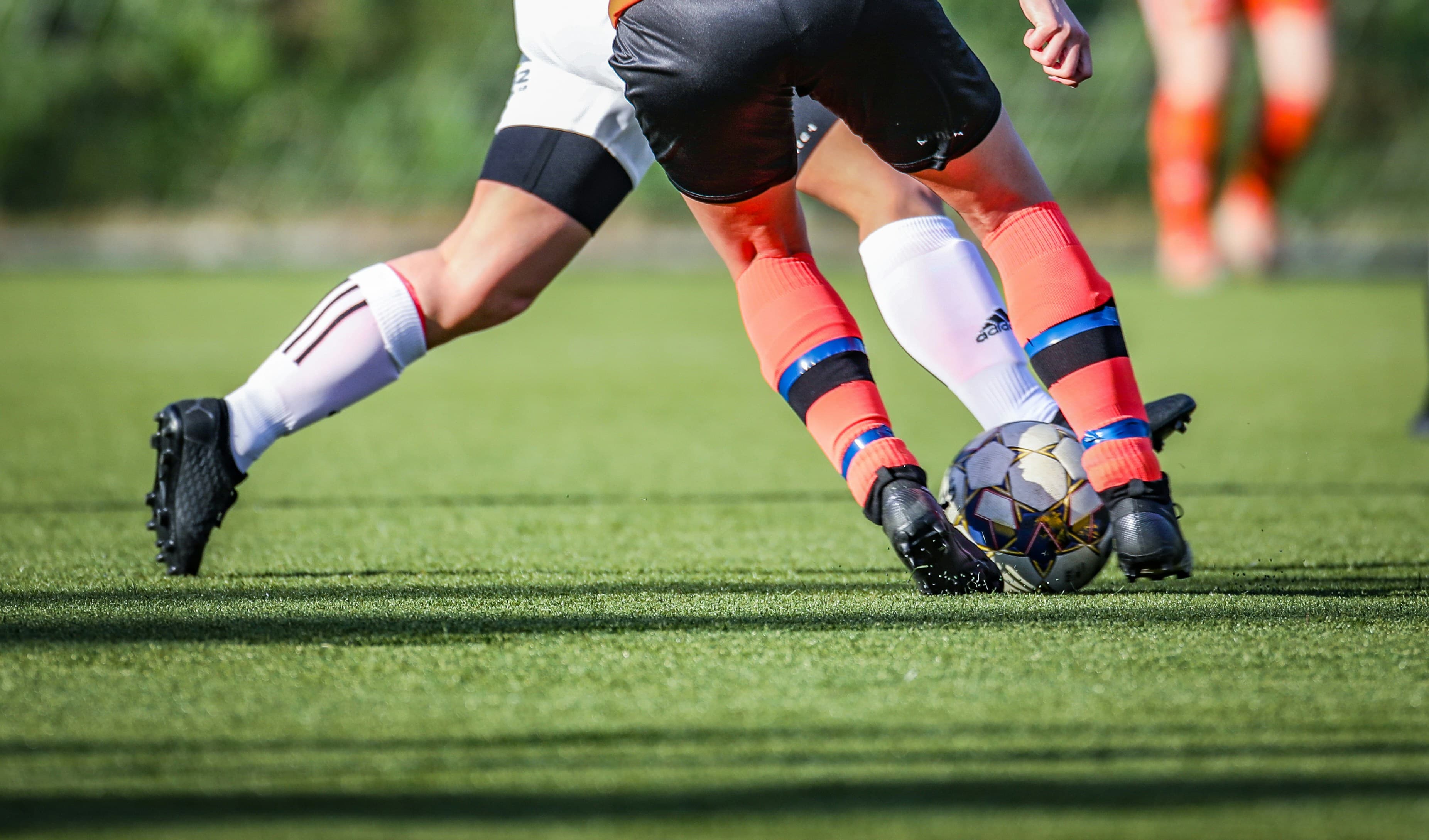 Two players battling for the ball on a sunlit pitch